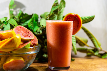Guava juice (Psidium guajava) and fresh fruits broken in a glass bowl