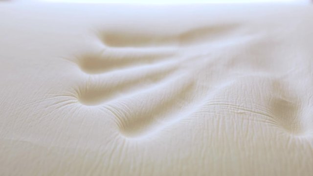 Mano sta toccando un materasso in poliuretano con tecnologia memory foam.