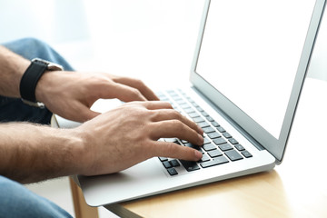Man working on modern laptop at wooden table indoors, closeup