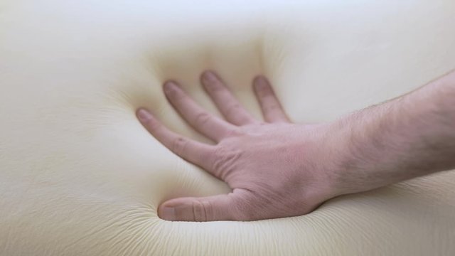 Mano sta toccando un letto in poliuretano con tecnologia memory foam.