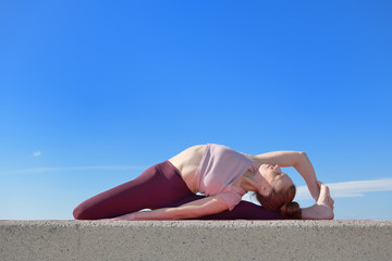 Fototapeta na wymiar Portrait of a fit woman who practices yoga outdoors. Woman practicing asanas on a sunny day