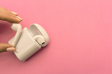 wireless headphones and wireless charging Case on pink background. Copy Space.