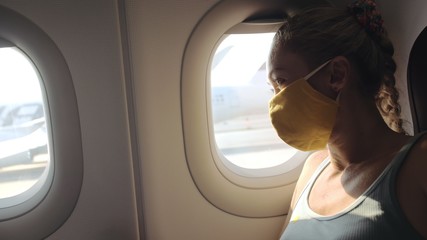 Woman travel caucasian at plane with wearing protective medical mask. Girl tourist at aircraft with protect respirator. Concept virus protection coronavirus epidemic sars-cov-2 covid-19 2019-ncov.