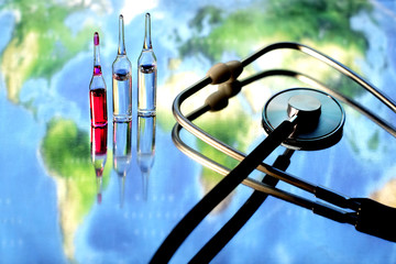 Medical equipment and a world map on the background. Global disease concept. Blurry world map, a stethoscope and ampoules.