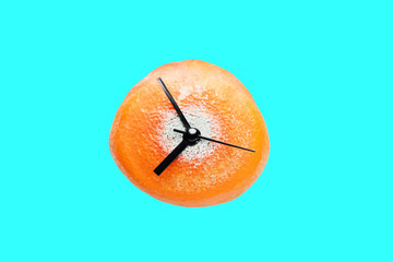 Decaying orange clock on a vivid aqua blue background. Wasting time concept. 