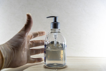 Human hand with disposable glove in motion to hold alcohol gel in Covid 19 prevention