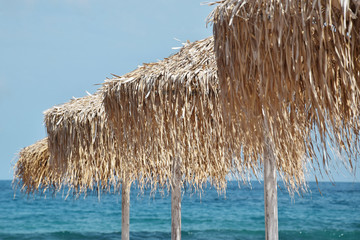 Beautiful Straw Beach umbrellas with Turquoise Sea in Background