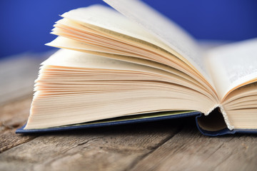 An open book on an old wooden table on a blue background.