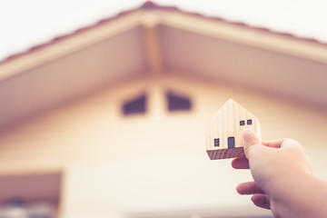 Hand holding House wooden model house blur background,property and real estate business concept