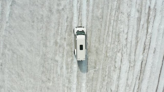 	Aerial footage of a white car driving on the glacier in Iceland