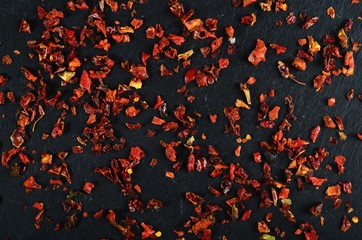Red chili flakes on a black stone background