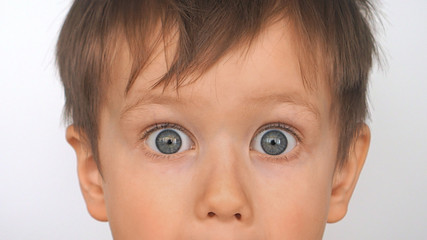 Baby with big eyes, surprised look. Boy with funny amazed expression, close-up