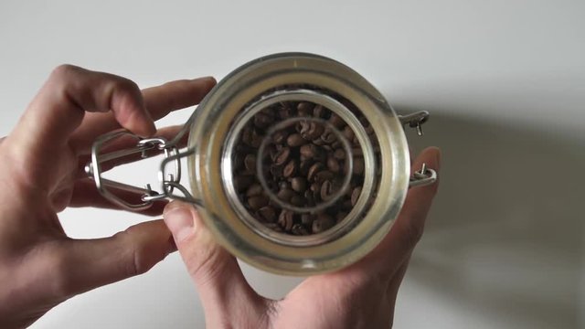 Close up opening jar fool of coffee beans. Slow motion action.