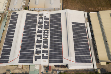 Aerial view of large energy efficient modern factory building with many solar panels neatly...