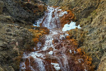 A small waterfall in Iceland. The volcanic rocks lying on the ground