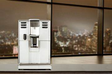 Coffee machine in office and blurred window of city at night 