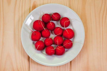 Red and ripe radish lying in a plate. Shot on a wooden background. Background for vegetables and healthy eating.