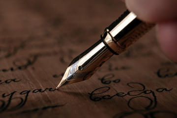 fountain pen in the hand with paper with ink text on the wooden desk