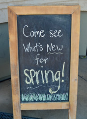 Fototapeta premium A sidewalk chalkboard sign invites customers into a local mom-and-pop store with the text 