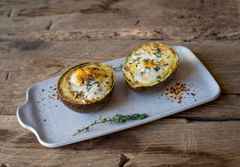 Baked avocado with eggs on wood deck.