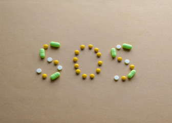 Inscription SOS of tablets on a light background. The concept of disease