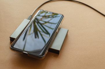 A phone is charging from a rectangular induction charger. Wireless charger