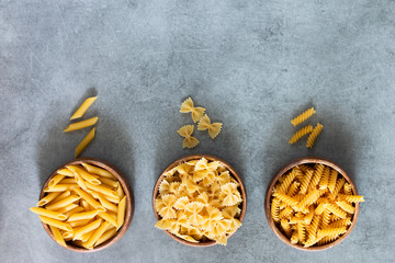 Different types of pasta on a grey background. Horizontal. copy space