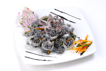 Peruvian seafood: closeup of black rice or risotto with octopus and calamari served on a white plate