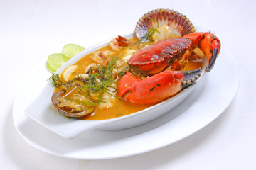 Peruvian food: closeup of a Parihuela or fish soup with crab and clams served on a white bowl