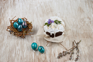 Easter painted eggs and cake on wooden backdrop. Top view.