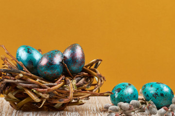 Colorful easter eggs with white points in straw nest on a wooden table