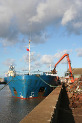 Ship being loaded with steel scrap by a crane, portrait view