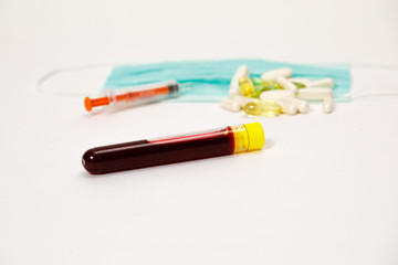 syringe for injection and test tube with blood, pills on a white background