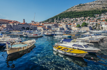 Fototapeta na wymiar Boats in Old Town Harbour in Dubrovnik. View with Revelin Fortress and Dominican Monastery, Croatia