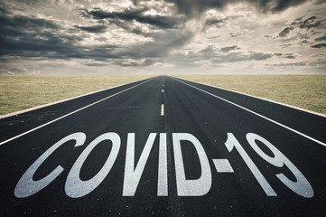 Covid-19 written on a road, dark clouds, coronavirus epidemic crisis concept