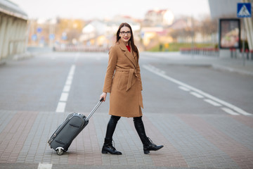 Full length portrait of smiling successful business man pulling suitcase at airport