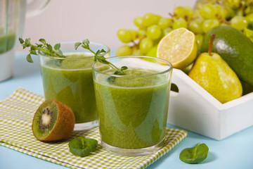 Fresh blended green smoothie in glasses with fruit and vegetables on the background. Health and detox concept.