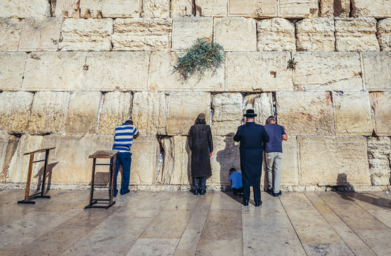 People prays in front of ancient limestone wall known as Wailing Wall in the Old City of Jerusalem, Israel