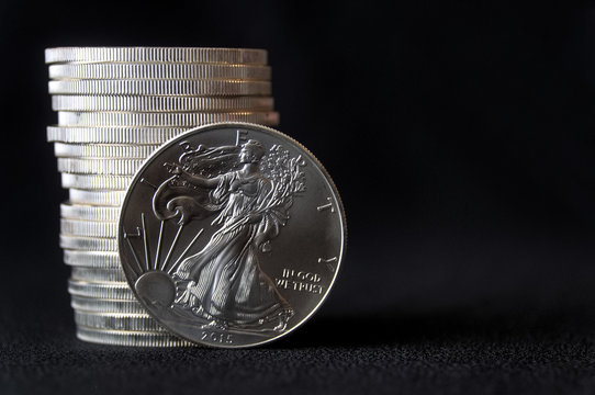 An American Silver Eagle coin, against a stack of silver eagle coins