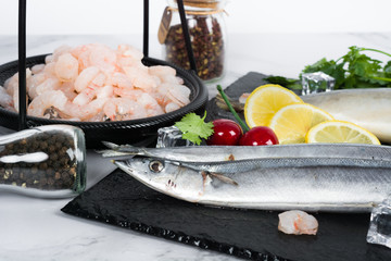 Fresh fish seabass and ingredients for cooking. Raw fish seabass with spices and herbs on black slate table. Top view.