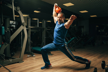 Senior man in his fifties lifting weights in a gym
