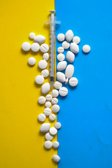 pills and capsules and syringe lie on color background.