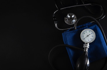 Old blood pressure meter monitor and stethoscope phonendoscope isolated on black background. Health care concept, copy space, top view.