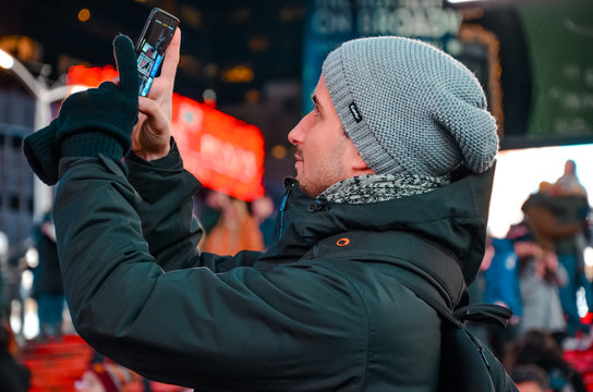 Mann am Times Square mit Smartphone im Winter