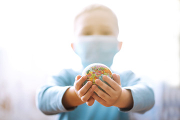 Child in protective sterile medical mask holding a world globe. Save planet. Planet sterilization....
