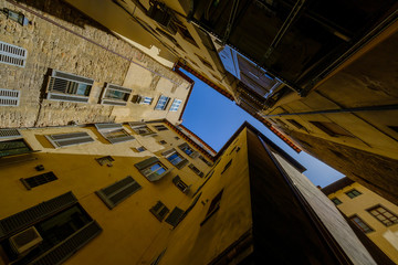 Fototapeta premium Narrow street view from the bottom up to the sky