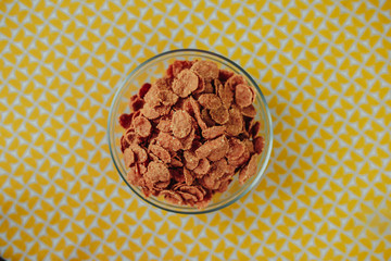 Healthy nutrition, healthy food on the table, dark cereal in the glass bowl on yellow table.