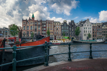 Houses on the Amstel canal with boats and a cloudy sky in Amster