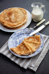 A stack of thin pancakes on a plate. Homemade pastries. Pancakes for breakfast. Appetizing food. Thin pancakes on a plate. Homemade crepes, tasty food. Staple of yeast pancakes.