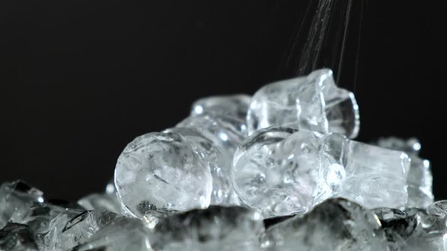 Drops of water fall on ice cubes. Close up.